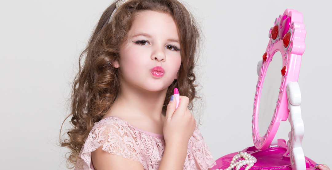 Cute little girl with lipstick applying makeup, glamour kid Beating